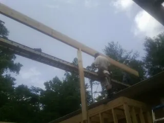 Carpenter setting a ridge beam over a new addition frame — Ice Dam Removal by Roofing Brothers in Howells