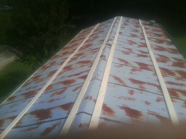 Rusted metal roof panels with new wood purlins before replacement — Storm Damage Roof Repair in Howells by Roofing Brothers
