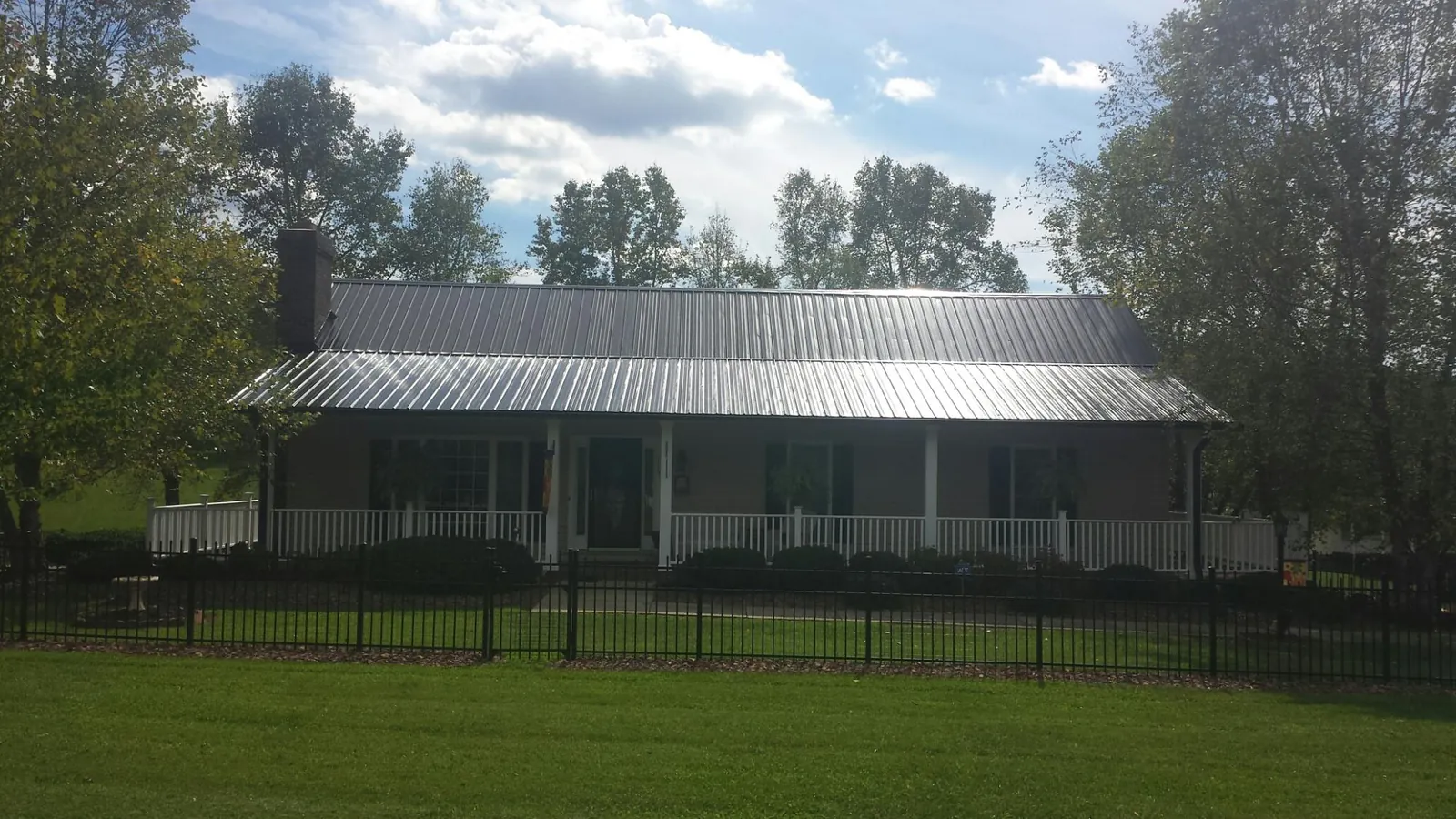 Gray metal roof on a brick ranch with a full width front porch — Gutter Guard Installation work by our crew in Howells