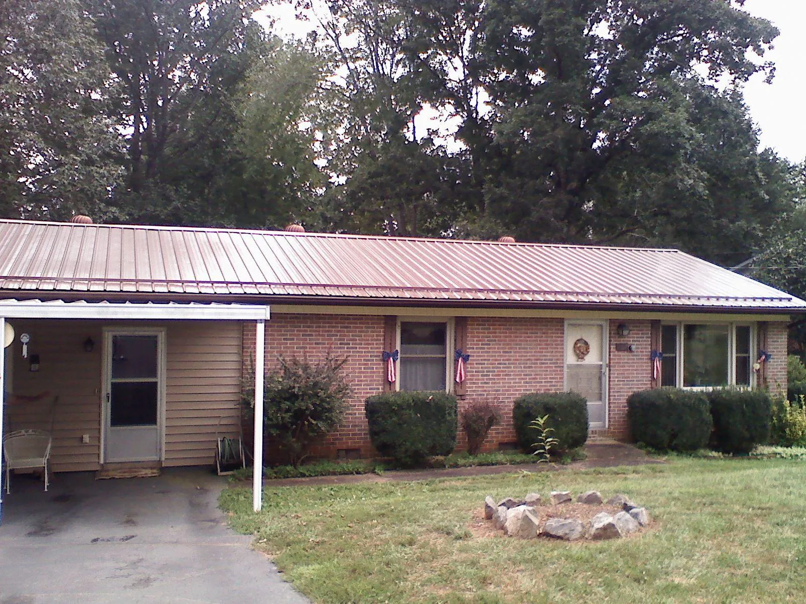 Bronze metal roof and carport on a brick ranch home — Roof Repair work by our crew in Howells