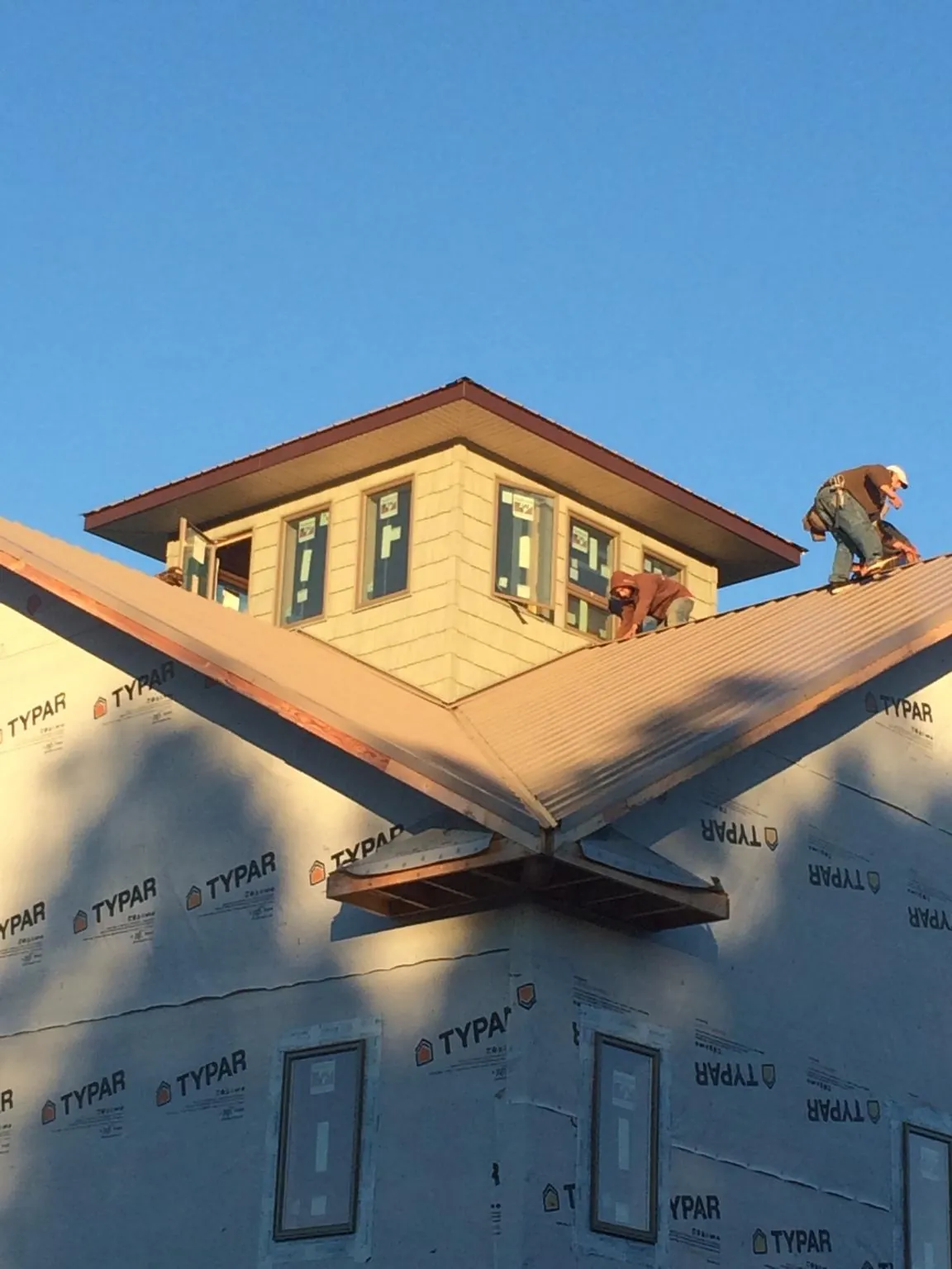 Roofers working around a rooftop cupola on a new metal roof at sunset — Roof Waterproofing in Howells by Roofing Brothers